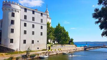 Un bâtiment doté d’une tour portant l’inscription « KAŠTEL » et offrant une vue sur le front de mer.