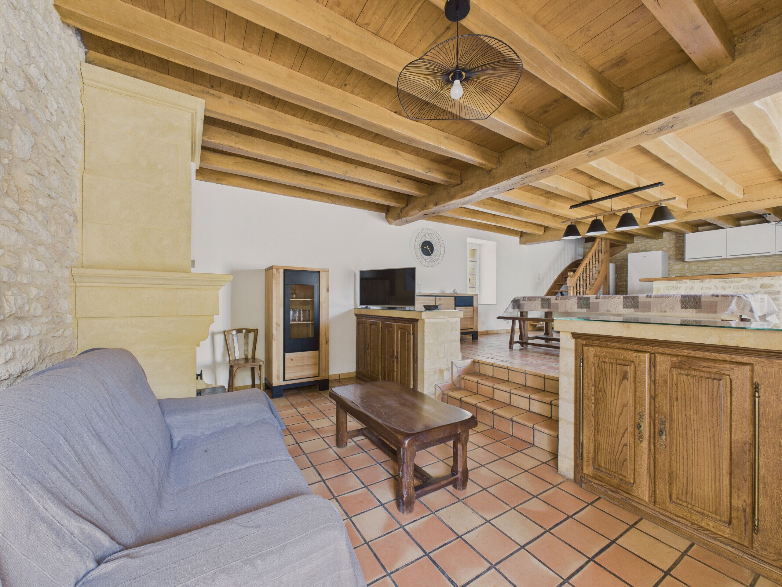 Ein gemütliches Wohnzimmer mit einer Couch, Holzschränken und einer Küchenzeile mit Treppe.