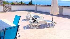 A terrace with a table, chairs, and an umbrella, overlooking a coastal view. - Sea view+parking, 100m to beach (Crikvenica)