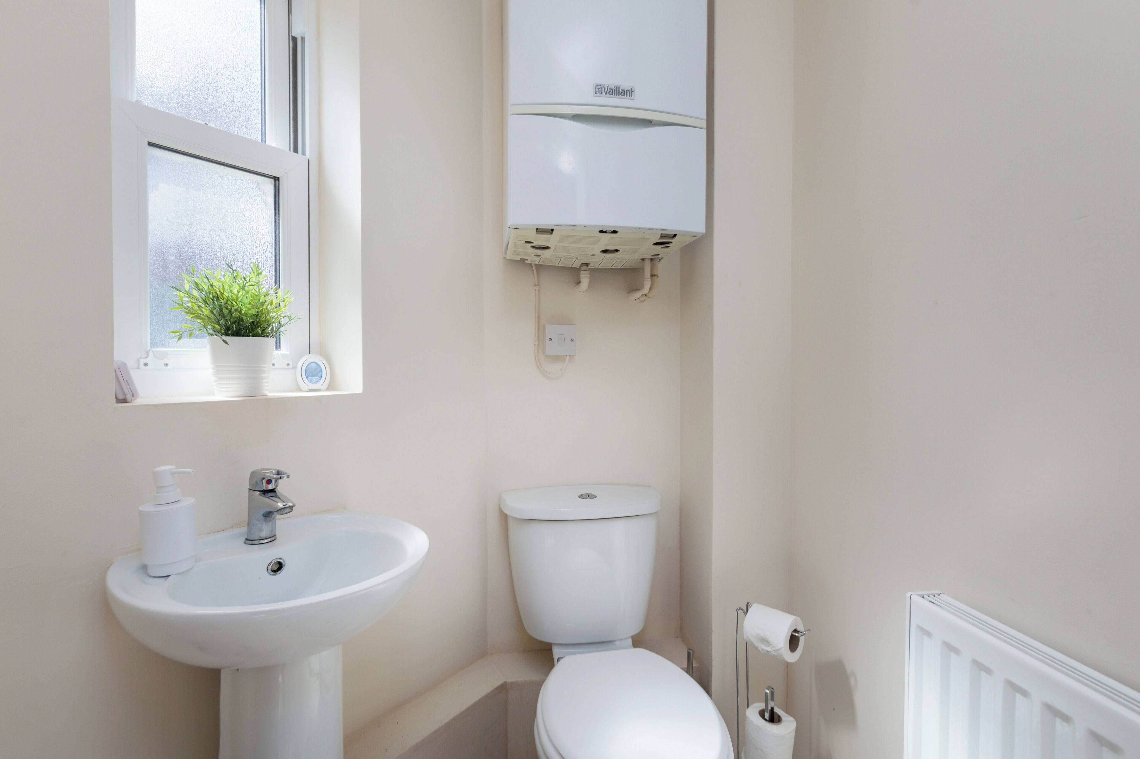 A bathroom with a white sink, toilet, and radiator.
