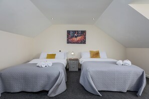 A hotel room with two beds, a painting on the wall, and a nightstand with a lamp. - House - Sleeps 10 - Parking - Wifi (Barrow-in-Furness)