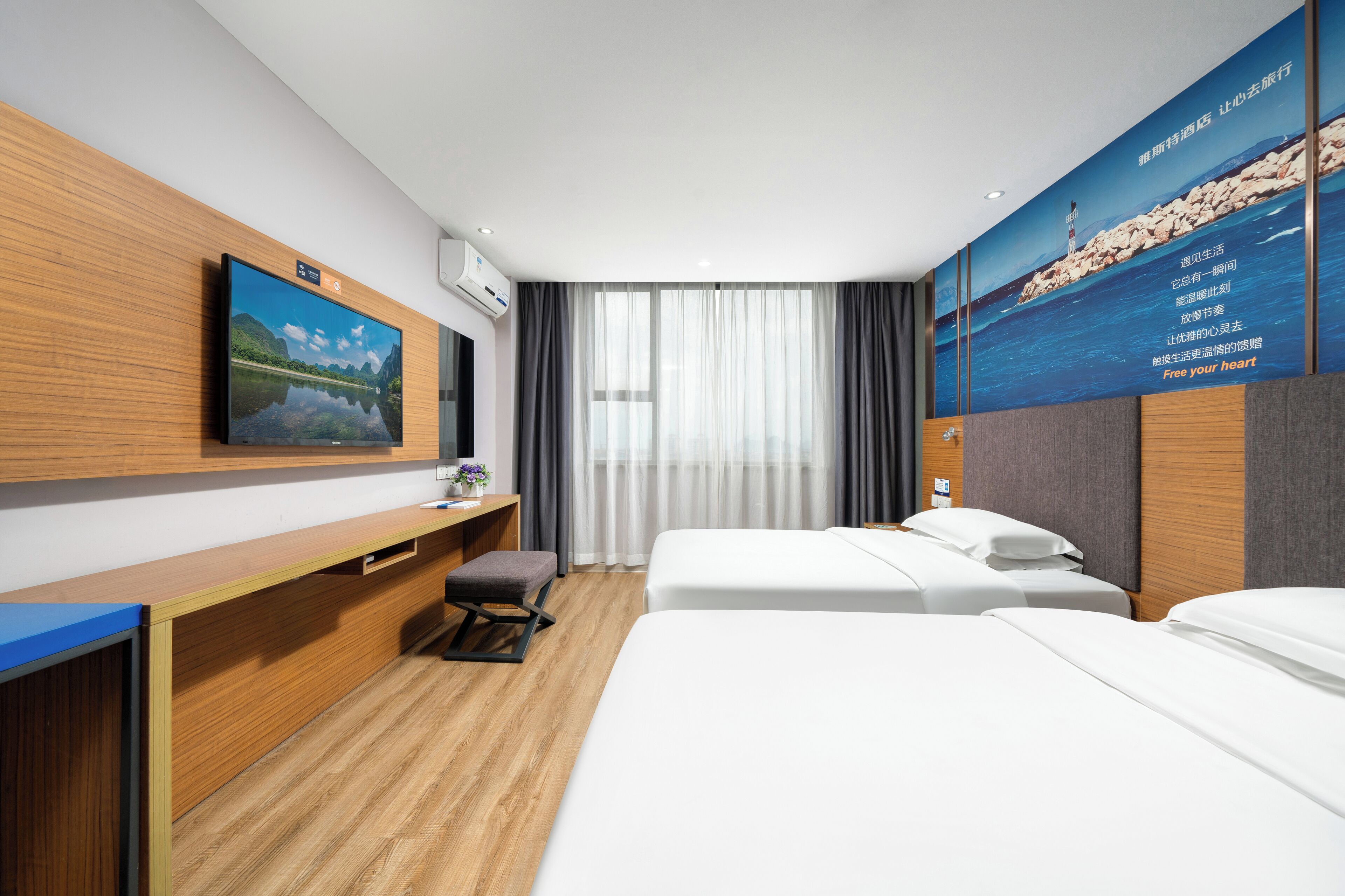 Een hotelkamer met een houten bureau, een flatscreen televisie, een bed en een groot poster aan de muur.