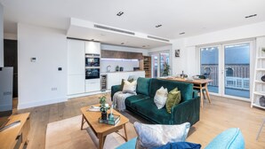 En moderne lejlighed med stue, spiseplads, køkken og en balkon med udsigt.