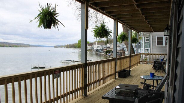 Um deck de madeira com vista para um lago, plantas penduradas e um aviso.