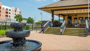 A scenic railway station with a covered waiting area, a fountain, and a staircase leading to the platform. - Condo next door to SDC (Branson)