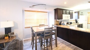 A compact kitchen with dark cabinets, a central island, and a dining area with a table and chairs. - Condo next door to SDC (Branson)