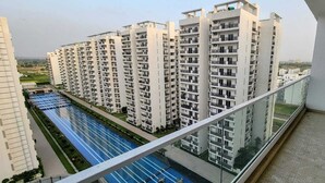 A high-rise residential building with multiple balconies and a swimming pool. - Ayaansh Resort (Sohna)