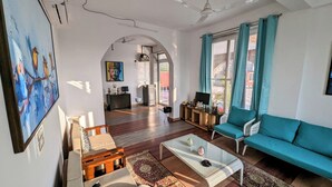 A spacious living room with a sofa, coffee table, and artwork on the walls. - Ayaansh Resort (Sohna)