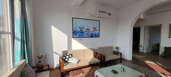 Un salon avec deux canapés, une table basse et un tableau accroché au mur.