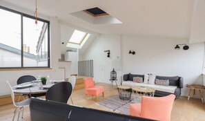 En moderne opholdsstue med spiseplads, en sofa, et lille bord og en trappe til et højere niveau.