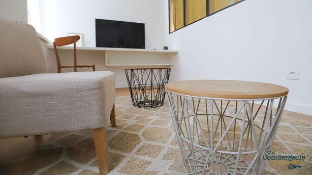 A modern living room with a sofa, a round table, and a TV on a white wall.