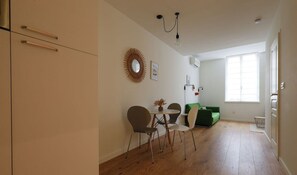 Uma sala de estar moderna com área de jantar, piso de madeira, um sofá verde e uma mesa de jantar com cadeiras.