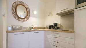 A kitchen with white cabinets, a wooden countertop, a coffee maker, and a hanging mirror.