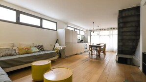 Un salon moderne avec un canapé, une table à manger et des poufs jaunes.