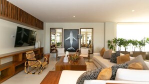 A modern living room with a flat-screen TV, a large abstract painting, a sofa set, and a coffee table.
