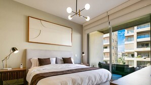 A modern hotel room with a large bed, a desk, a chair, a large window, and a view of the city.