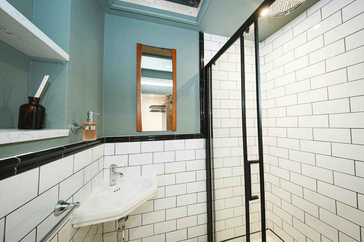 A bathroom with a white sink, a mirror, and a shower area.
