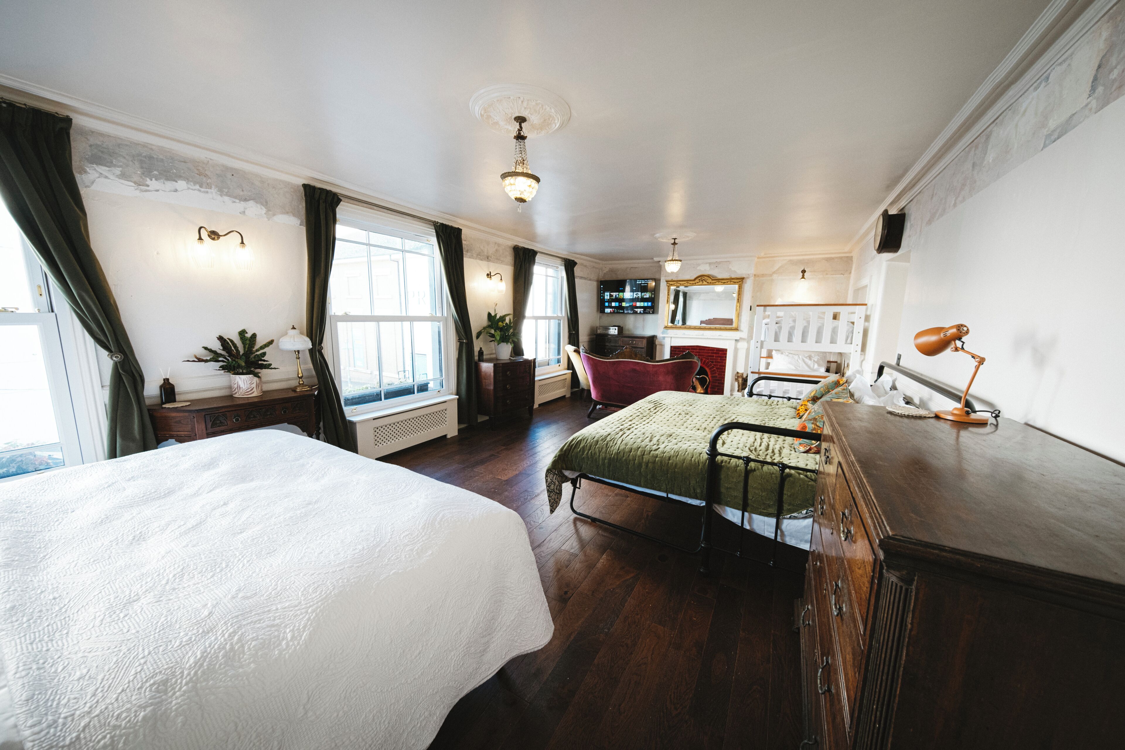 A hotel room with two beds, a desk, a chair, a television, and a large window.