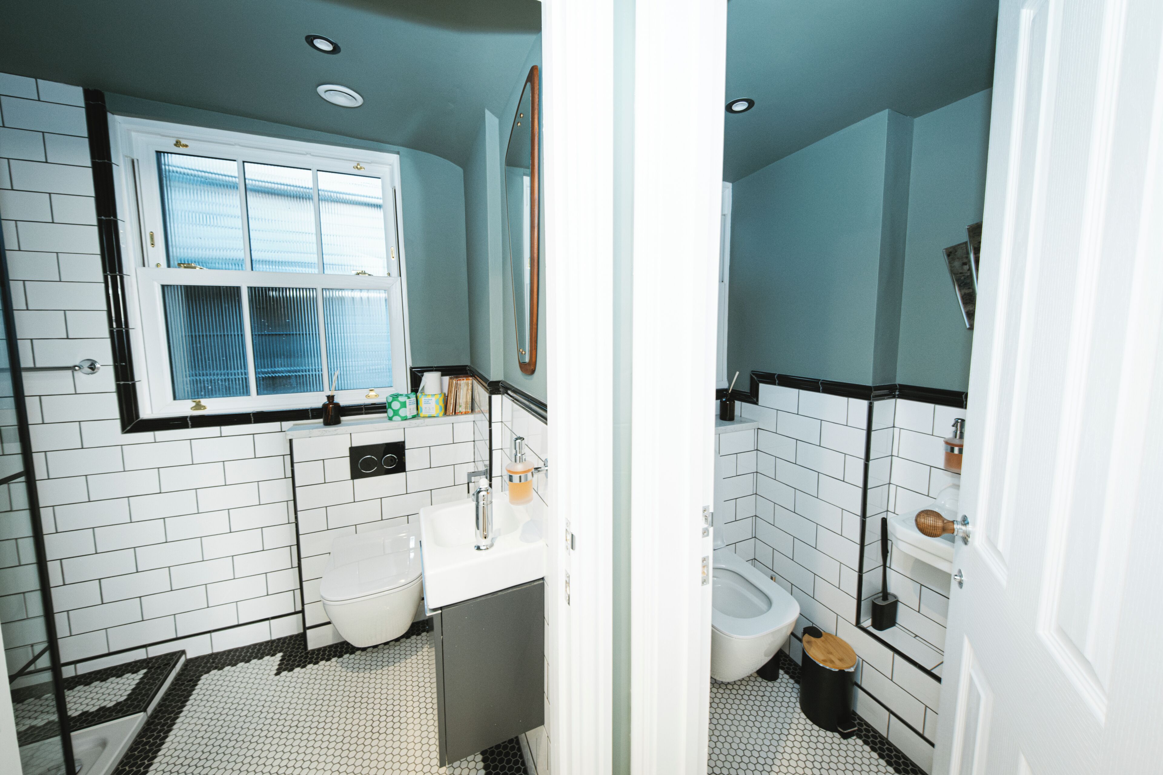 A bathroom with a white sink, toilet, and bidet, tiled in white and black.