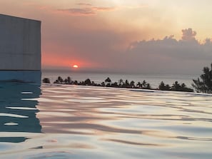 A sunset over a beach with a concrete structure on the left. - Apartment with ocean views near the beach and restaurants, featuring a rooftop pool. (Flic en Flac)