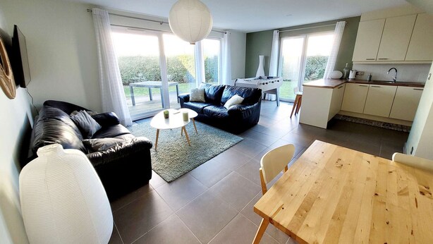 A modern living room with a sofa, a dining table, and a kitchen area. - Modern villa 3 bedrooms with garden, WiFi and parking, close to beach (Wimereux)