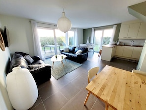 A modern living room with a sofa, a dining table, and a kitchen area. - Modern villa 3 bedrooms with garden, WiFi and parking, close to beach (Wimereux)