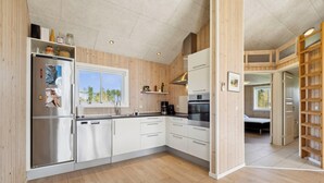 A modern kitchen with white cabinets, stainless steel appliances, and a wooden floor. - Modern holiday home from 2017, located at Lild Strand. (Frøstrup)