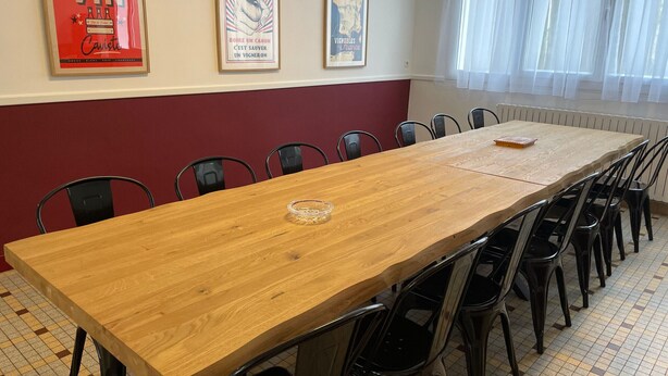 A conference room with a long wooden table, black chairs, and three framed posters on the wall.