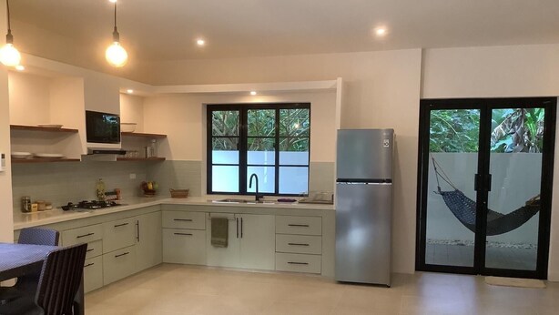 Una cocina moderna con comedor, refrigerador y ventana con vista a follaje.