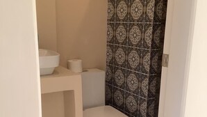 Un baño pequeño y funcional con inodoro, lavamanos blanco y cortina de ducha estampada.