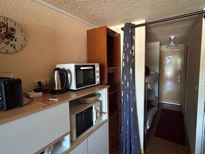 Eine kompakte Küchenzeile mit Mikrowelle, Toaster und Wasserkocher auf einer Holzausziehtischplatte.