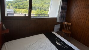Hotellihuone, jossa on suuri ikkuna, josta avautuu näkymä vehreään maisemaan.