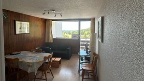 Kompakti huone, jossa on ruokapöytä, tuoleja, sohva ja parveke, jolta on kaunis näköala.