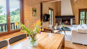 Un interior de madera con una mesa de comedor, sofá blanco y una chimenea.