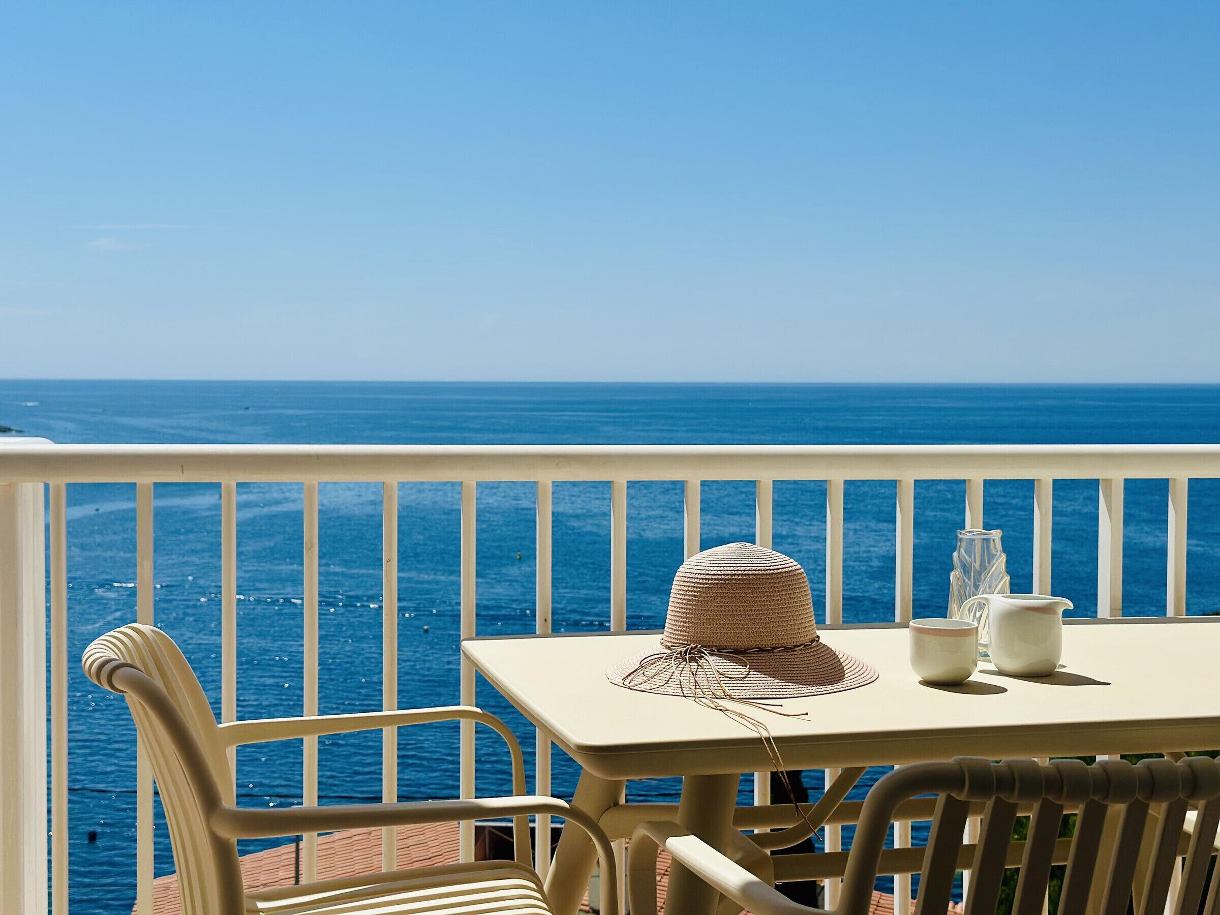 A balcony with a table, chairs, and a hat.