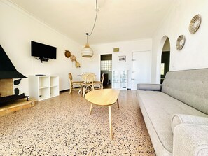 A living room with a sofa, a table, chairs, a TV, and a fireplace.