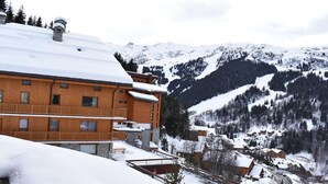 A wooden building with balconies, surrounded by snow-covered mountains and trees. - 4-room apartment for 6 guests, parking and balcony in Méribel (Méribel)