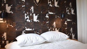 A bedroom with a cowhide wall, a mounted deer head, two black wall sconces, and a bed with white bedding. - 4-room apartment for 6 guests, parking and balcony in Méribel (Méribel)
