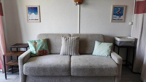 En grå sofa med mønstrede puder, et træhovedgærde og en vægmonteret lampe.
