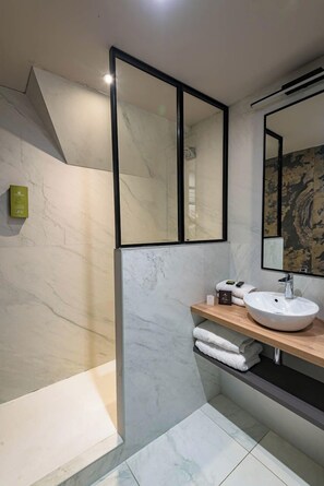A modern bathroom with a marble floor, a wooden vanity, a white sink, and a large mirror. - Appartements de la Cité - Saint Malo (Saint-Malo)