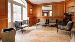 A spacious living room with wooden paneled walls, a large window, and a fireplace.