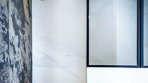 A bathroom with a marble wall and a glass partition.