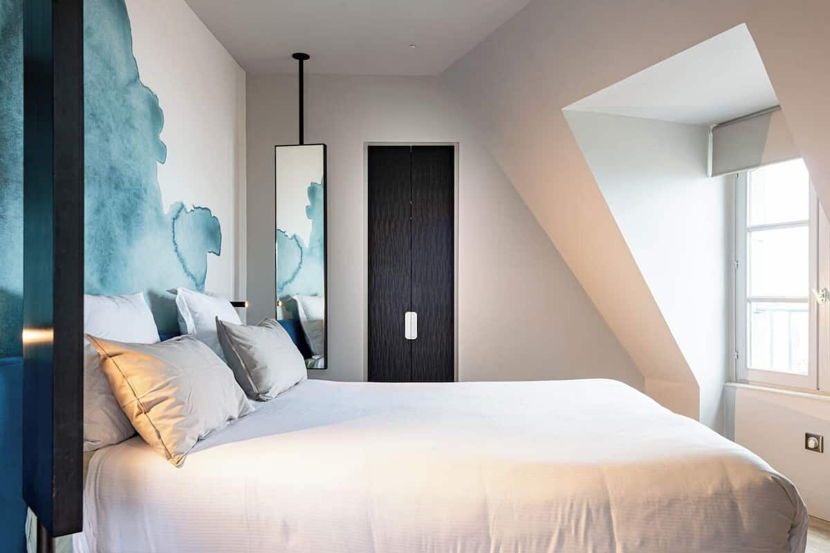 Un dormitorio moderno con una cama grande, un armario oscuro y un tragaluz.