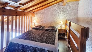 A bedroom with a skylight, wooden beams, a bed with patterned bedding, and two bedside tables with lamps. - Cozy Duplex in La Clusaz - 5 pers, pets allowed (La Clusaz)