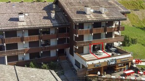 A multi-story building with a pub on the ground floor, balconies, and a ski lift in the background. - Studio La Clusaz for 4 people, Pets allowed, 32 m² (La Clusaz)