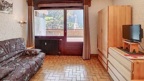 A cozy room with a sofa, wooden wardrobe, and a television on a stand. - Studio La Clusaz for 4 people, Pets allowed, 32 m² (La Clusaz)
