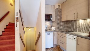 A kitchen with a microwave, toaster, and dishwasher. There is a staircase with red carpet leading to a door. - Studio La Clusaz for 4 people, Pets allowed, 32 m² (La Clusaz)