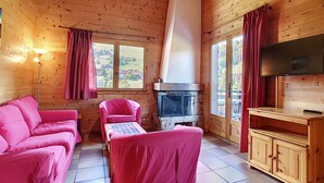 A cozy cabin with a fireplace, a television, and a pink sofa.