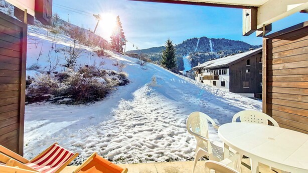 A snow-covered outdoor area with a wooden building, a table, and chairs. - Cozy studio in La Clusaz, 4 pers, pets allowed (La Clusaz)