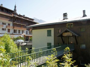 A building with a wooden facade, a signboard, and a staircase leading to a balcony. - 64m² Apartment La Clusaz, 7 people, Pets Allowed, WiFi (La Clusaz)